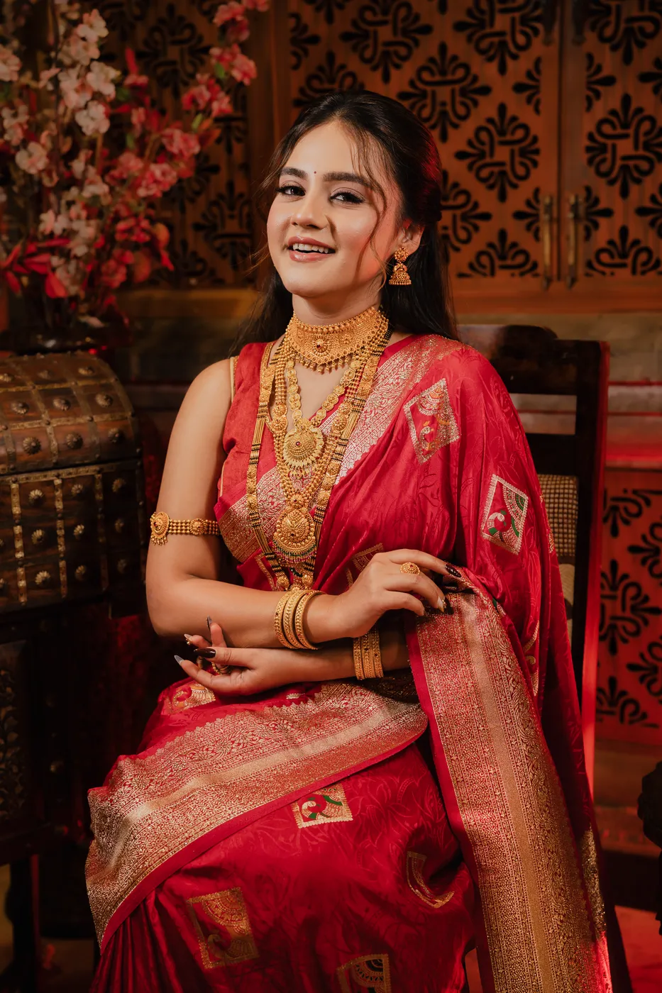 Smiling model wearing layered gold necklaces, bangles and jhumkas from Baba Jewellers