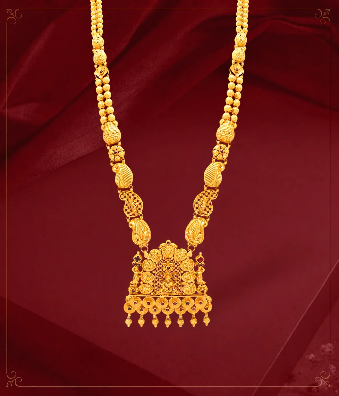 Long gold temple-style necklace arranged on maroon fabric
